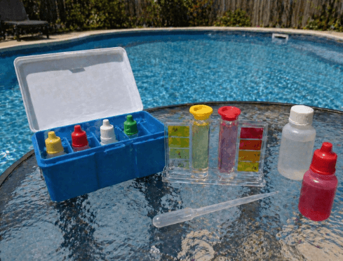 Pool water testing kit on a table beside a swimming pool